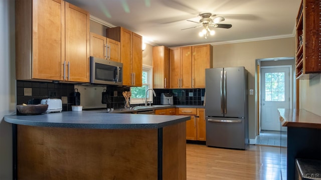 kitchen with plenty of natural light, ornamental molding, stainless steel appliances, and light hardwood / wood-style flooring