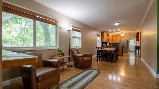 living room featuring light wood-type flooring, crown molding, and a healthy amount of sunlight