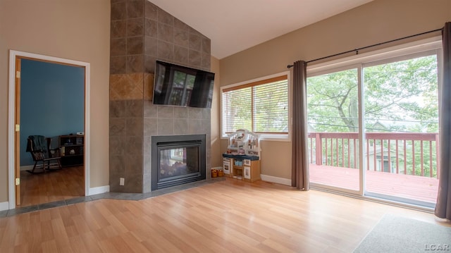 unfurnished living room with a fireplace, hardwood / wood-style flooring, tile walls, and lofted ceiling