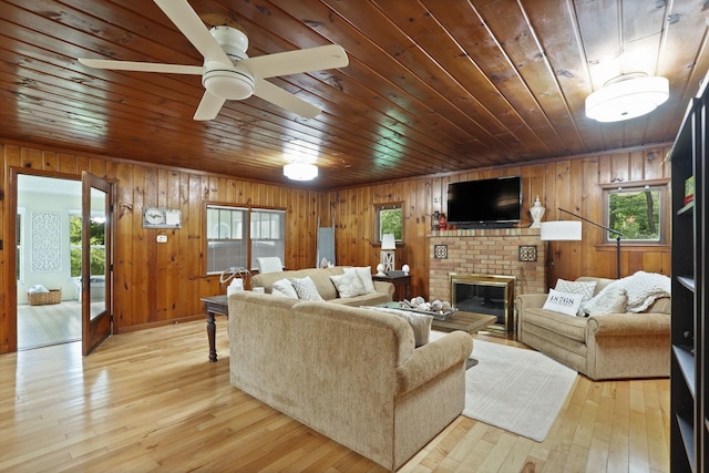 living room with a brick fireplace, wooden walls, light hardwood / wood-style flooring, and wooden ceiling