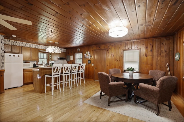 dining area featuring light hardwood / wood-style floors, plenty of natural light, wooden ceiling, and wood walls