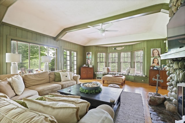 living room featuring ceiling fan, wood walls, hardwood / wood-style floors, lofted ceiling, and a fireplace