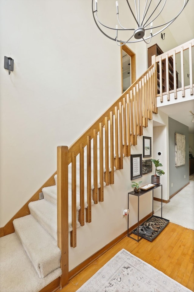 stairs with hardwood / wood-style floors and an inviting chandelier