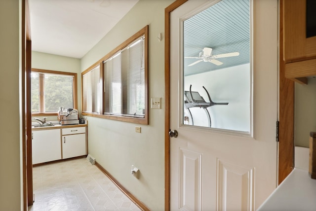 doorway with ceiling fan, light tile patterned floors, and sink