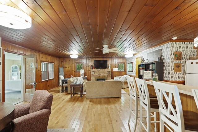 9300 Ormes Rd, Vassar, MI 49768 - living room with wood ceiling, a ceiling fan, light wood-style flooring, a brick fireplace, and wood walls