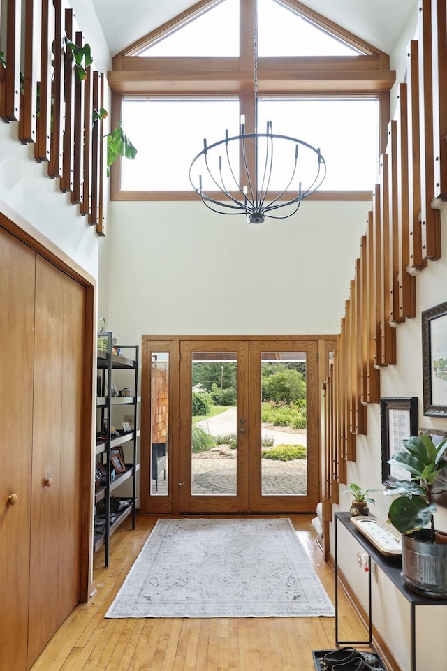 foyer featuring a chandelier, french doors, high vaulted ceiling, and light hardwood / wood-style flooring