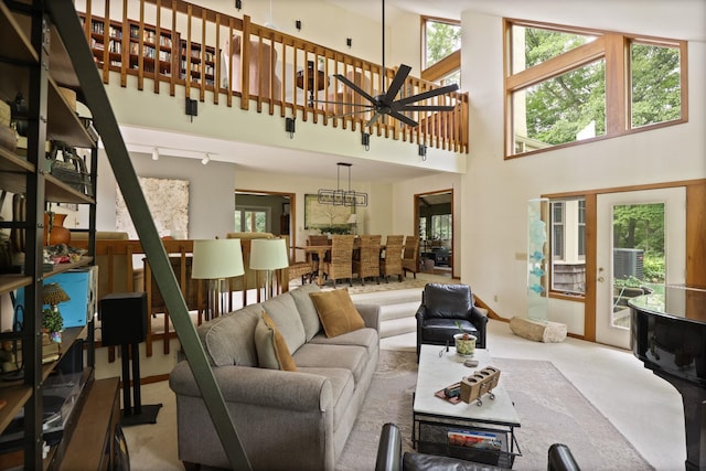 carpeted living room with ceiling fan and a towering ceiling