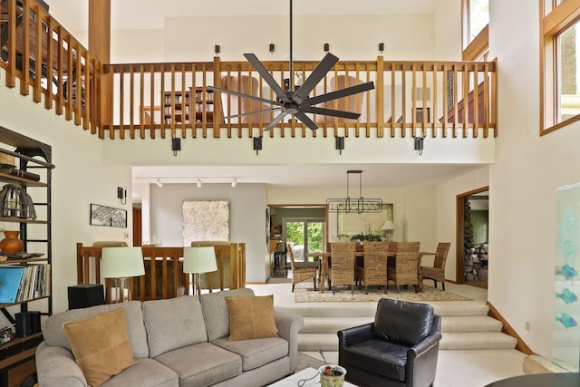 living room with carpet flooring, a towering ceiling, track lighting, and ceiling fan