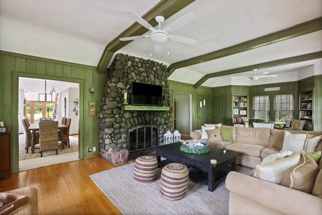 9300 Ormes Rd, Vassar, MI 49768 - living room featuring hardwood / wood-style floors, a ceiling fan, a stone fireplace, and wood walls