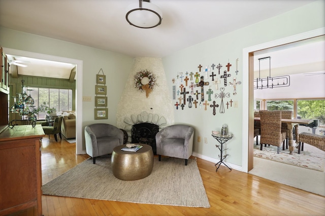 sitting room with a fireplace, hardwood / wood-style floors, and ceiling fan