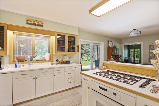 kitchen with white appliances, white cabinetry, and sink