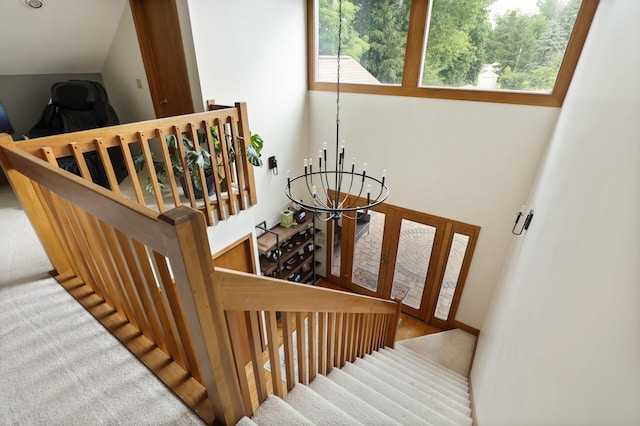 stairs featuring a chandelier, carpet flooring, and a wealth of natural light