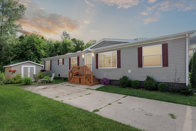 manufactured / mobile home featuring a lawn and a storage unit