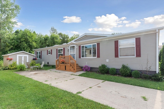 manufactured / mobile home with a patio, a front yard, and a storage shed