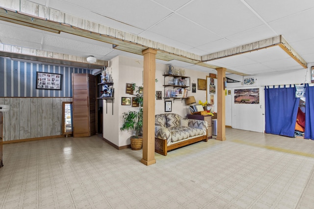 interior space with a drop ceiling and wooden walls