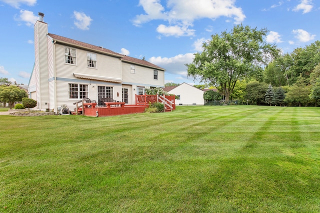 rear view of house featuring a yard and a deck