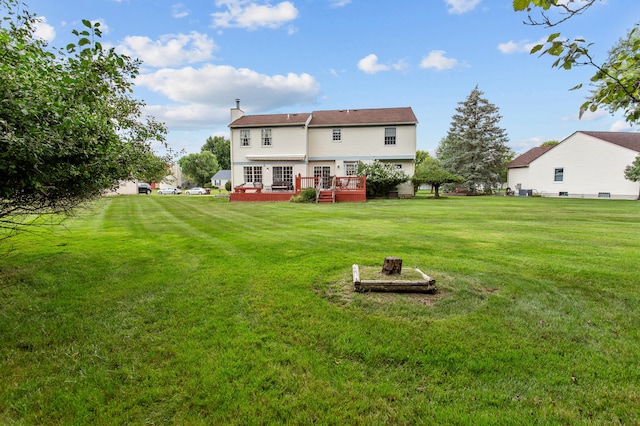 rear view of house featuring a lawn and a wooden deck