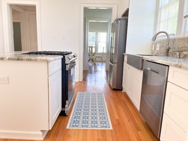 kitchen featuring white cabinetry, sink, appliances with stainless steel finishes, and light hardwood / wood-style flooring