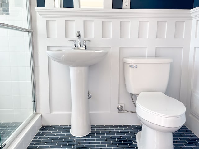 bathroom with tile patterned flooring, toilet, and an enclosed shower