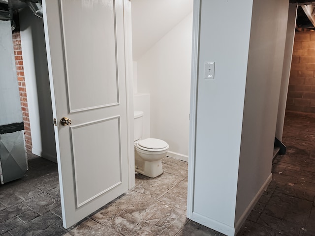 bathroom with brick wall and toilet