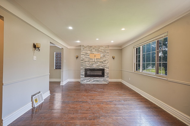 unfurnished living room with a stone fireplace, dark wood-type flooring, and ornamental molding