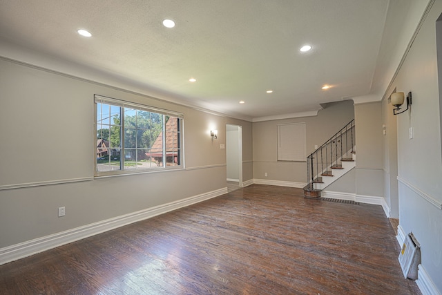 unfurnished room with a textured ceiling, crown molding, and dark wood-type flooring