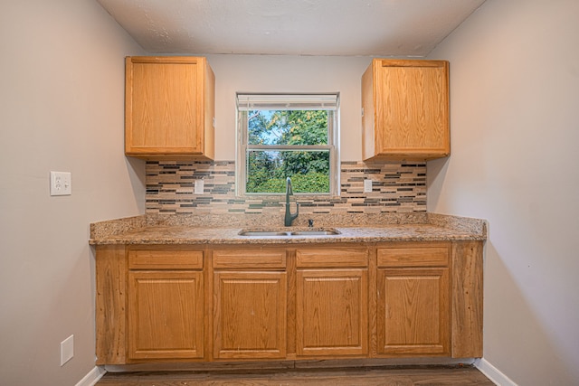 kitchen featuring decorative backsplash, light stone countertops, and sink