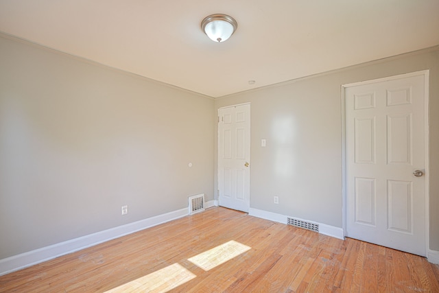 spare room with light hardwood / wood-style floors and crown molding