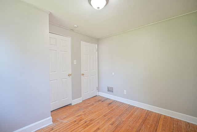 spare room with crown molding and light wood-type flooring