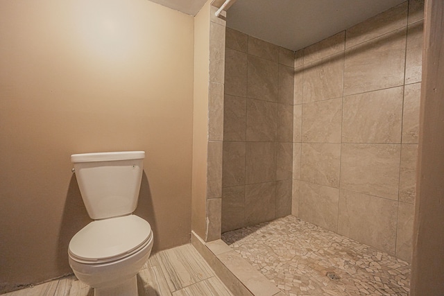 bathroom featuring tiled shower and toilet