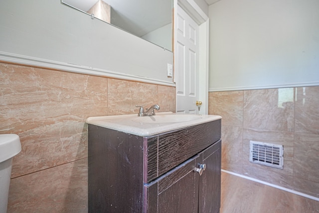 bathroom with vanity, toilet, wood-type flooring, and tile walls