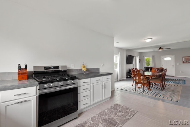 kitchen with ceiling fan, gas stove, white cabinetry, and light hardwood / wood-style flooring