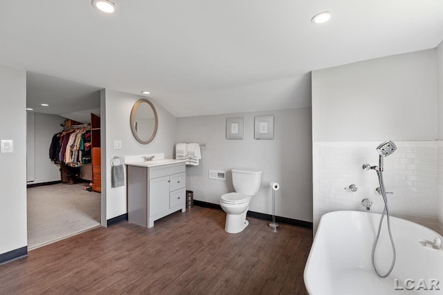 bathroom with hardwood / wood-style flooring, vanity, toilet, and a bath