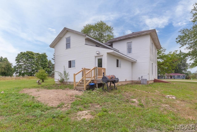 rear view of house with central AC unit and a yard