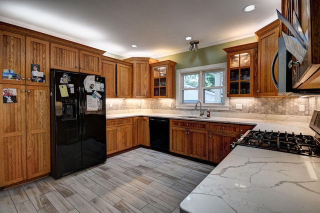 417 Barlow St, Traverse City, MI 49686 - kitchen featuring black appliances, a sink, brown cabinetry, light stone counters, and crown molding