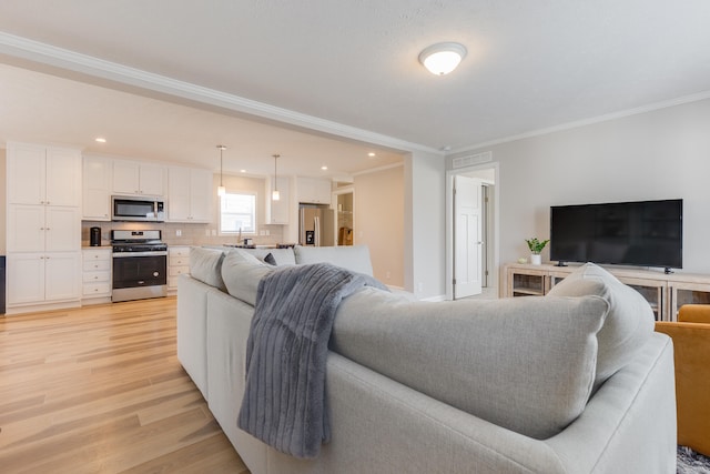 living room with crown molding, sink, and light hardwood / wood-style floors