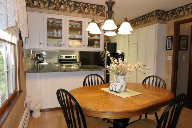 dining space featuring baseboard heating, sink, and hardwood / wood-style floors