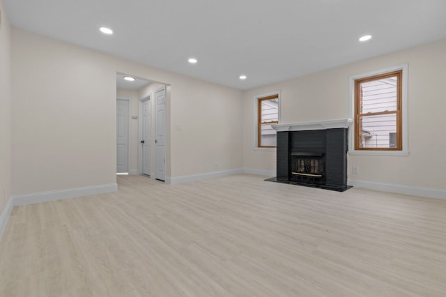 unfurnished living room with a fireplace, plenty of natural light, and light hardwood / wood-style floors