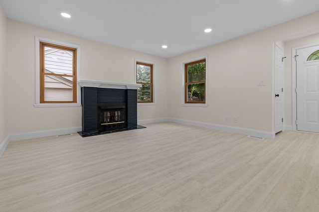 unfurnished living room with light wood-type flooring and a brick fireplace