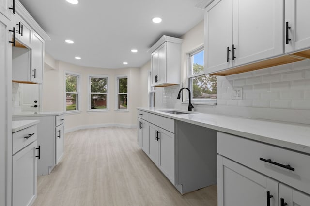 kitchen with light hardwood / wood-style flooring, white cabinetry, a healthy amount of sunlight, and sink