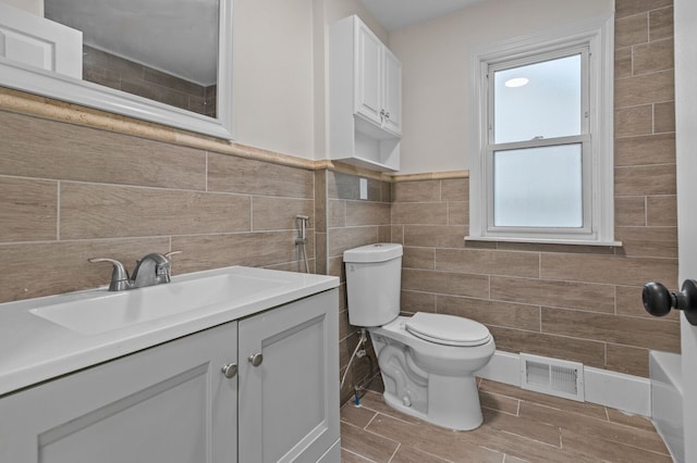 bathroom featuring vanity, a wealth of natural light, and tile walls