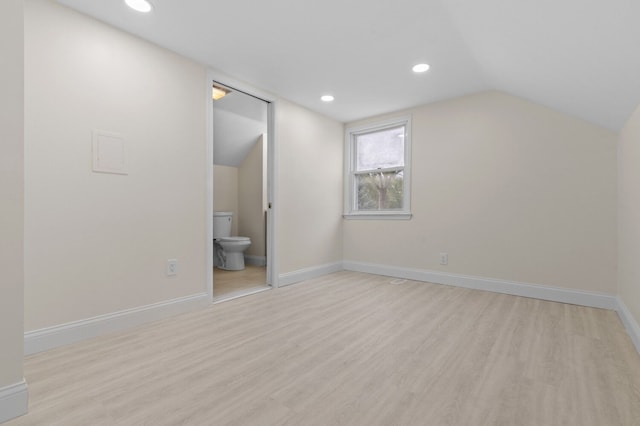 additional living space featuring light wood-type flooring and vaulted ceiling