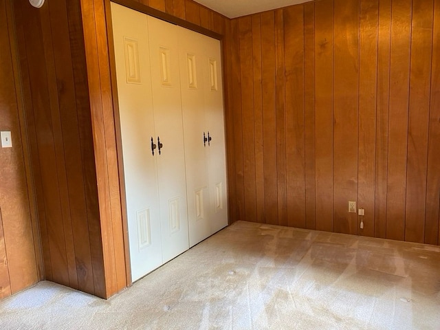 unfurnished bedroom with wood walls and light carpet