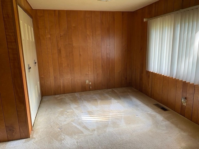 carpeted empty room featuring wooden walls