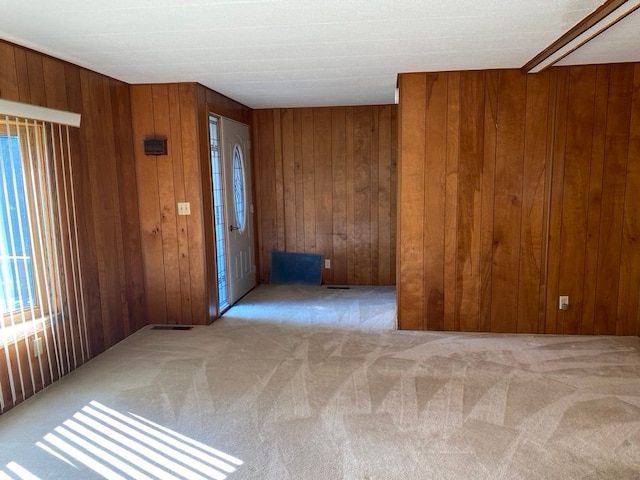 entryway featuring wood walls and light colored carpet