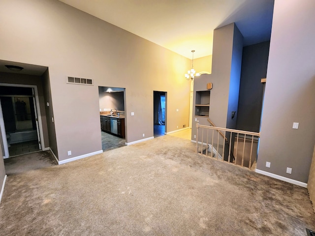 unfurnished living room featuring dark colored carpet, a towering ceiling, a notable chandelier, and sink