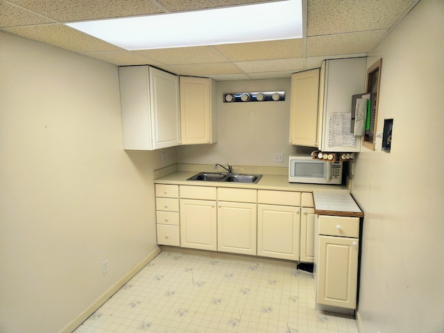 kitchen featuring a paneled ceiling, white cabinetry, and sink