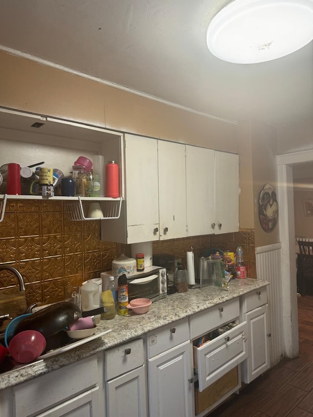 kitchen with white cabinetry, sink, dark wood-type flooring, light stone counters, and decorative backsplash