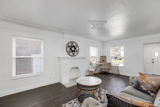 living room with a textured ceiling, dark hardwood / wood-style flooring, and a brick fireplace