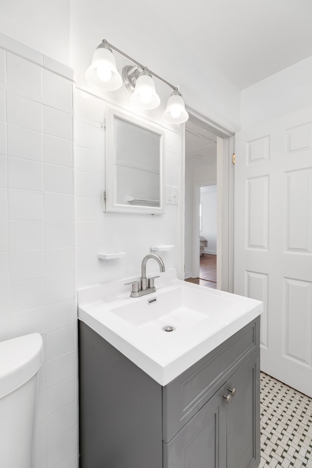 bathroom featuring vanity, tile walls, and toilet